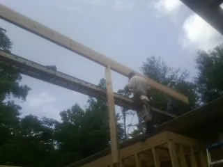 Carpenter setting a ridge beam over a new addition frame — Ice Dam Removal by Roofing Brothers in Fruita