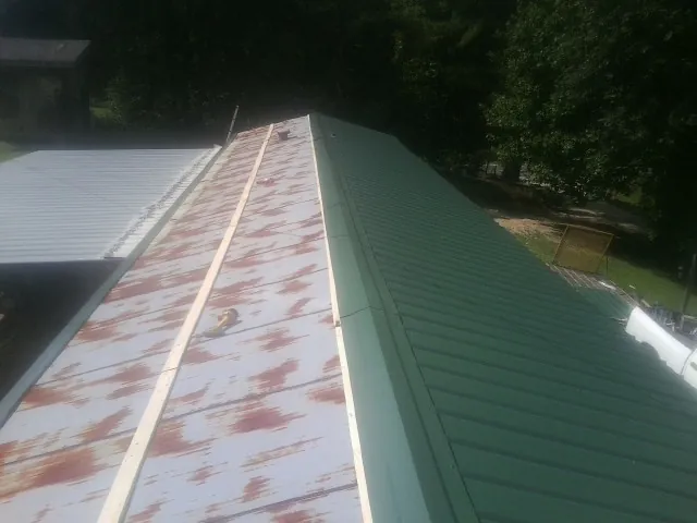 Old rusted panels beside newly installed green metal roofing — Wind Damage Roof Repair by Roofing Brothers in Fruita