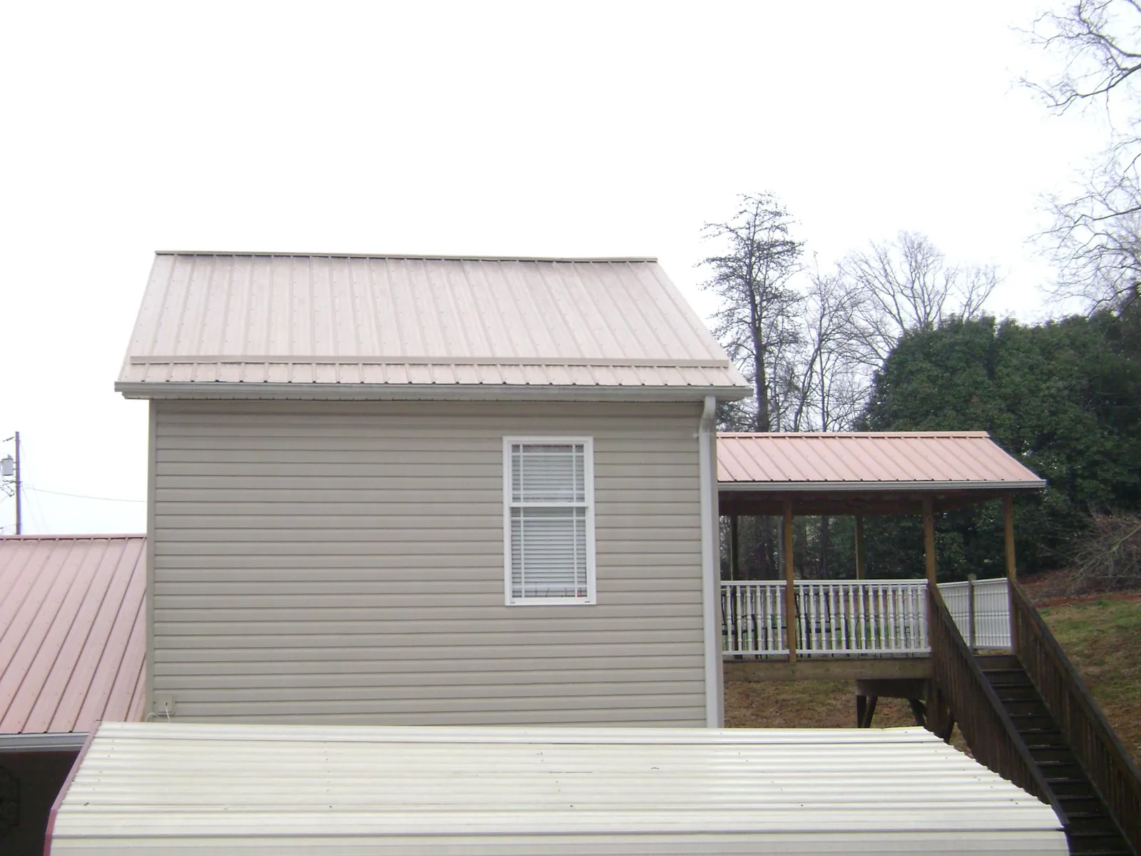 Tan metal roofs on a two story addition and attached porch, from a Roof Replacement job in Fruita