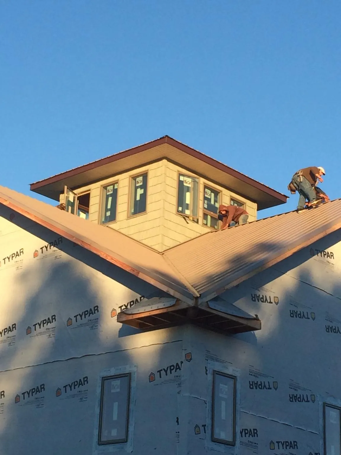 Roofers working around a rooftop cupola on a new metal roof at sunset — Roof Waterproofing in Fruita by Roofing Brothers